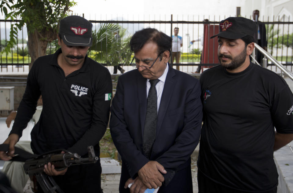 Saiful Malook, center, defense lawyer for Asia Bibi, a Pakistani Christian woman charged with blasphemy, looks at a gun belonging to his body guard as he leaves the Supreme court after a proceeding, in Islamabad, Pakistan, Monday, Oct. 8, 2018. A three judge panel of Pakistan's Supreme Court on Monday postponed its ruling on a final appeal by Bibi, who has been on death row since 2010 on blasphemy charges. Malook pointed out contradictions in several statements given to support the charge of blasphemy. (AP Photo/B.K. Bangash)