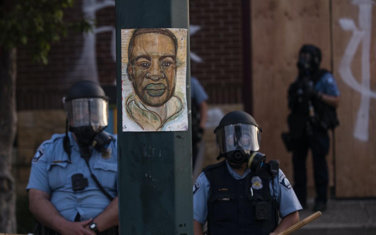 <span class="caption">A portrait of George Floyd hangs on a street light pole as police officers stand guard at the Third Police Precinct during a face off with a group of protesters on May 27, 2020 in Minneapolis. </span> <span class="attribution"><a class="link " href="https://www.gettyimages.com/detail/news-photo/portrait-of-george-floyd-hangs-on-a-street-light-pole-as-news-photo/1215796055?adppopup=true" rel="nofollow noopener" target="_blank" data-ylk="slk:Stephen Maturen/Getty Images;elm:context_link;itc:0;sec:content-canvas">Stephen Maturen/Getty Images</a></span>