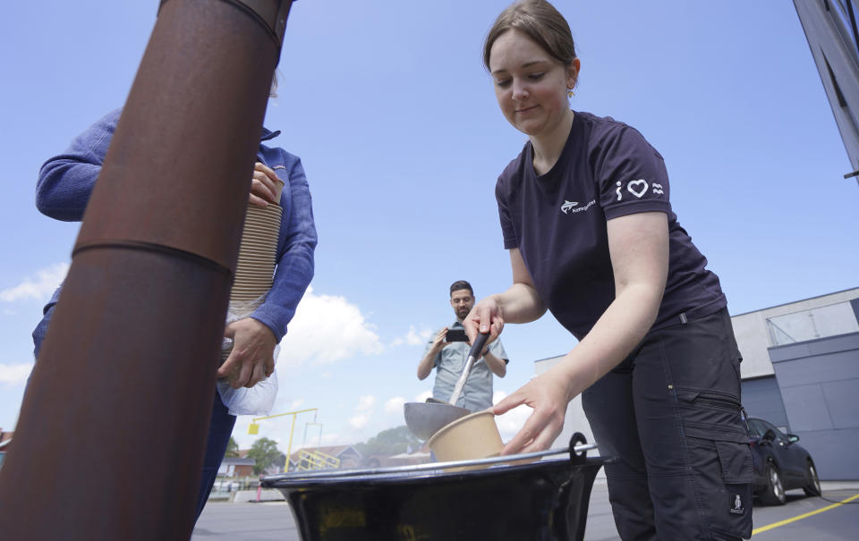 A woman serves mussel soup with seaweed garnish at Klintholm Harbour, Klintholm, Denmark, Tuesday June 18, 2024. (AP Photo/James Brooks)