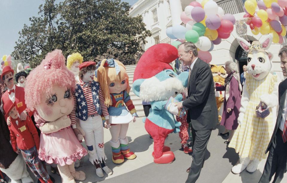 U.S. Vice President George H. Bush greeted by cartoon characters at the start of the annual Easter egg roll on the White House, April 8, 1985 in Washington. (AP Photo) ORG XMIT: APHS205201 [Via MerlinFTP Drop]