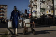 Residents affected by Hurricane Ian walk home with drinking water in containers in La Coloma, in Pinar del Rio province, Cuba, Wednesday, Oct. 5, 2022. (AP Photo/Ramon Espinosa)