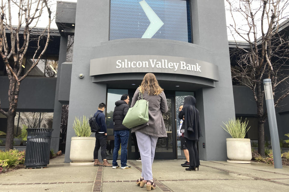 People stand outside of an entrance to Silicon Valley Bank in Santa Clara, Calif., Friday, March 10, 2023. The Federal Deposit Insurance Corporation seized the assets of the bank on Friday, marking the largest bank failure since Washington Mutual during the height of the 2008 financial crisis. (AP Photo/Jeff Chiu)