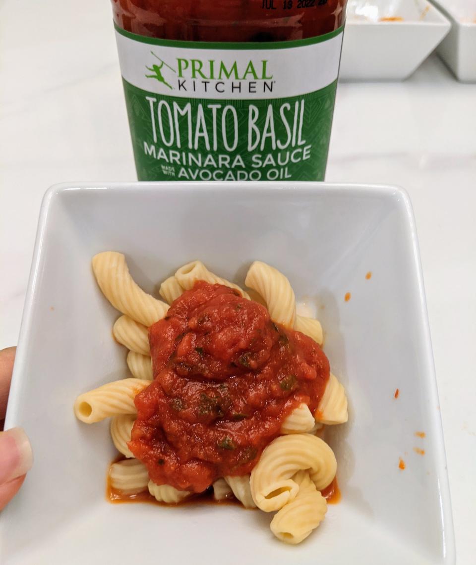 jar of primal kitchen sauce behind a small white bowl of pasta