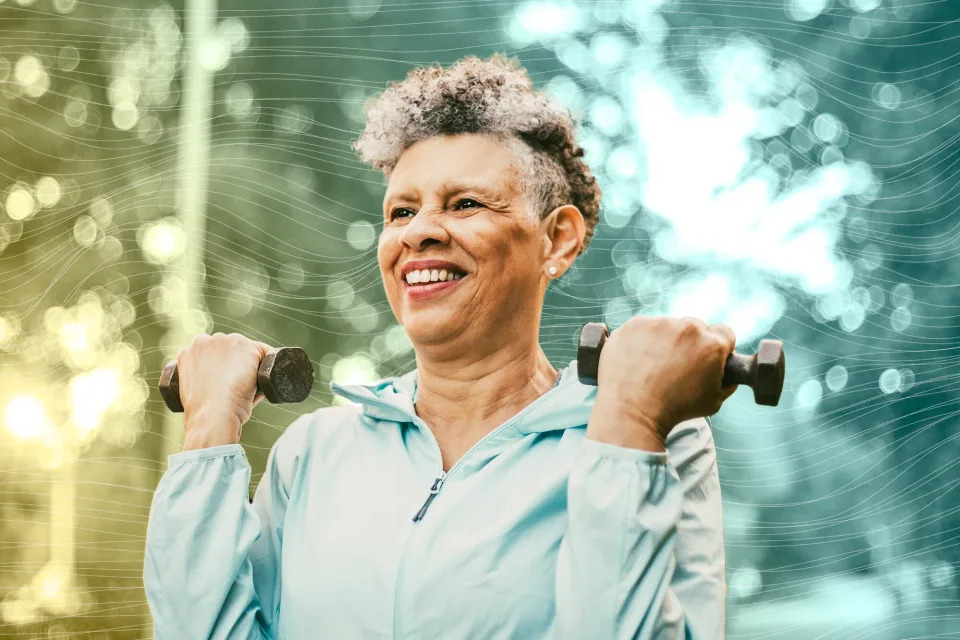 Smiling senior woman with dumbbells exercising in park