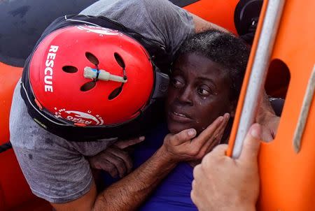 A crew member of NGO Proactiva Open Arms rescue boat embraces African migrant in central Mediterranean Sea. REUTERS/Juan Medina