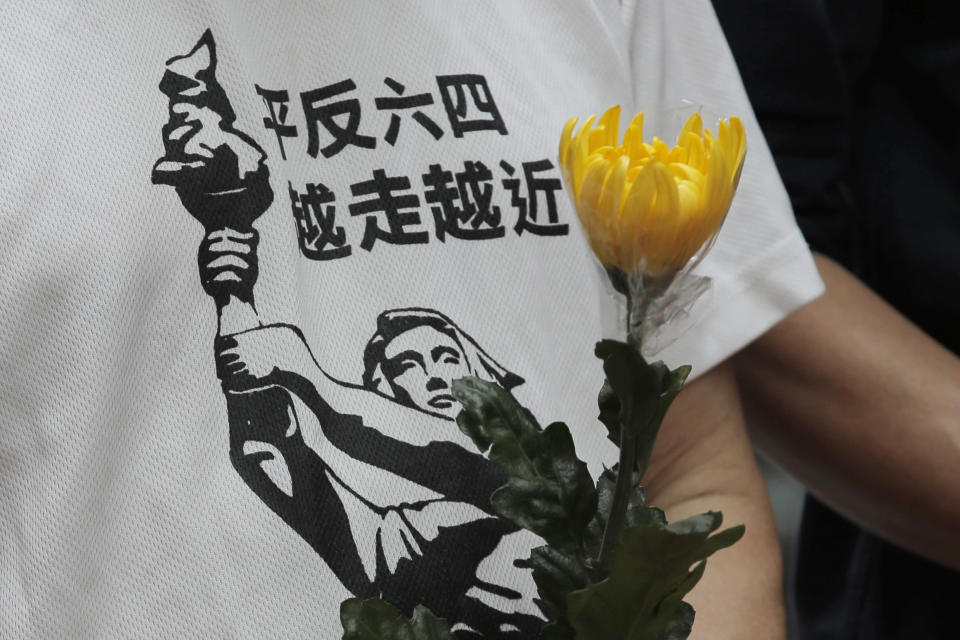 A protester wearing T-shirt with Chinese words that read "Exonerate the June 4 protest, move closer", holds flower to commemorate the June 4, 1989 military crackdown in Beijing's Tiananmen Square on a pro-democracy student movement, in the University of Hong Kong, Friday, May 4, 2018. Tens of thousands of people are expected to attend an upcoming annual candlelight vigil on June 4 to remember those killed when their protest in Beijing. (AP Photo/Kin Cheung)