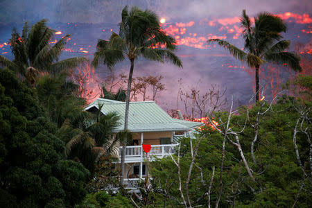 Lava flows near a house on the outskirts of Pahoa during ongoing eruptions of the Kilauea Volcano in Hawaii, U.S., May 19, 2018. REUTERS/Terray Sylvester