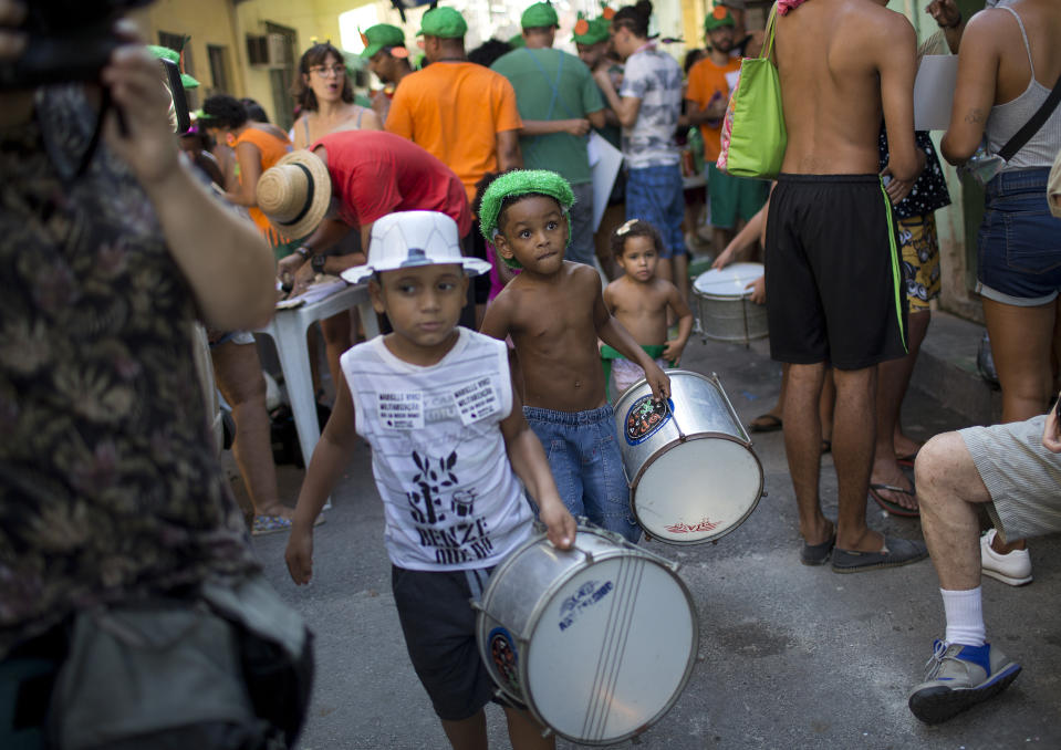 Boys bring their drums to the "Se Benze que da" block party, which was created by slain councilwoman Marielle Franco, in the Mare slum of Rio de Janeiro, Brazil, Saturday, Feb. 23, 2019. Merrymakers take to the streets in hundreds of open-air "bloco" parties ahead of Rio's over-the-top Carnival, the highlight of the year for many. (AP Photo/Silvia Izquierdo)