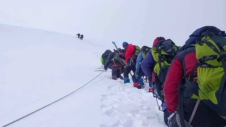 The NIM trainees climb in a queue on the slopes of the peak prior to the slide