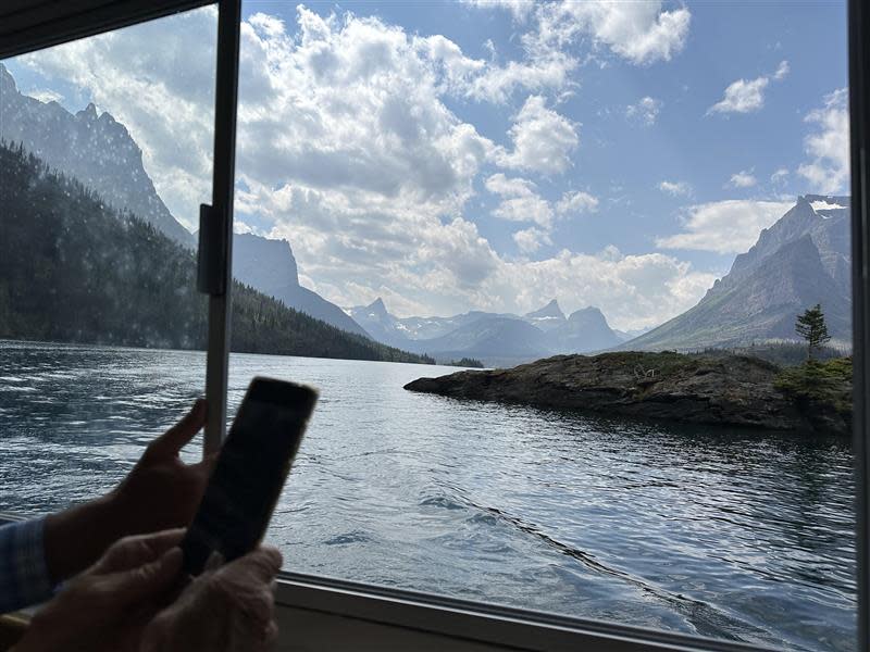 A tourist takes pictures of Wild Goose Island while on a scenic tour of St. Mary Lake at Glacier National Park.