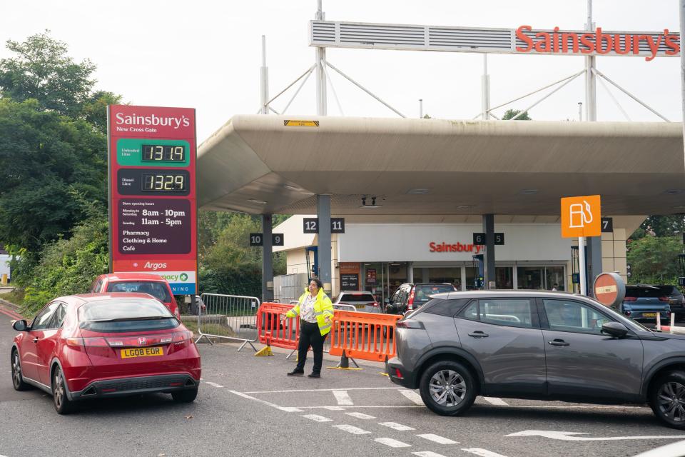 A member of staff directs motorists trying to queue for fuel at a Sainsbury’s petrol station in south London (PA)