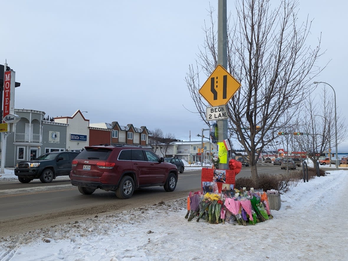 Flowers and posters commemorating Aaron Smarch lay alongside 4th Avenue Whitehorse Saturday. RCMP say Smarch's death is being ruled a homicide. (Chris Windeyer/CBC - image credit)