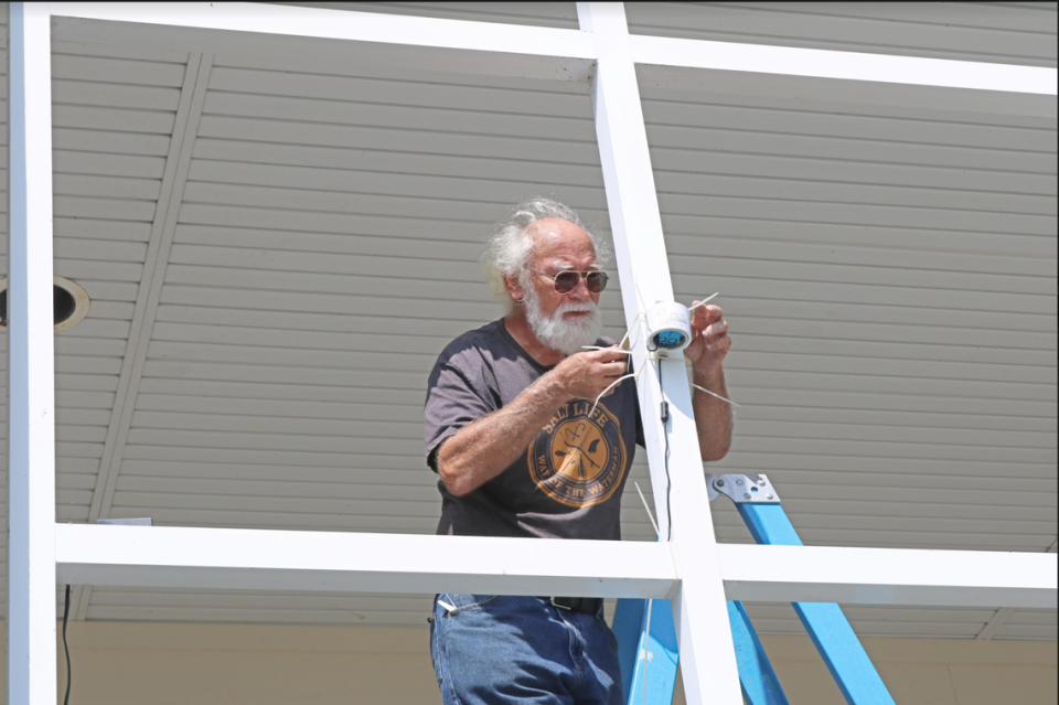 Steve Karl, a member of Chowan-Edenton Environmental Group, installs an air quality device, July 22, 2022. The device detects particulate matter and the data is displayed on a real-time map maintained by the device manufacturer PurpleAir. Researchers will use the air quality data to study airborne algal blooms in northeast NC.