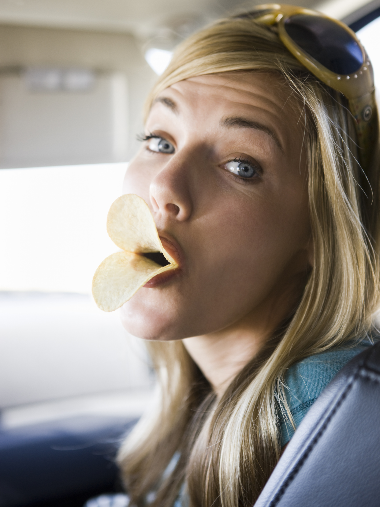 Woman Making Duck Lips With Pringles in Her Mouth, Sitting on Passenger's Side