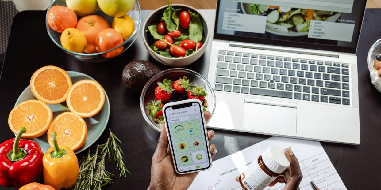 woman's hands holding vitamin pill bottle surrounded by dietary notes and healthy food to represent biohacking