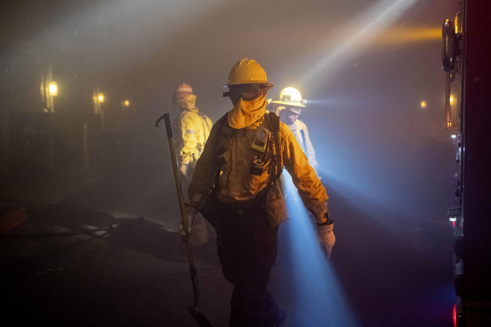 In this Thursday, Oct. 10, 2019 photo, firefighters check on homes in smoke from the Saddleridge fire in Sylmar, Calif. (Photo: Michael Owen Baker/AP)