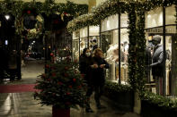 FILE - In this Wednesday, Nov. 25, 2020 file photo, women wearing face masks walk past a Christmas tree and lights in Burlington Arcade, where all non-essential shops are temporarily closed during England's second coronavirus lockdown, in London. Nations are struggling to reconcile cold medical advice with a holiday tradition that calls for big gatherings in often poorly ventilated rooms, where people chat, shout and sing together, providing an ideal conduit for a virus that has killed over 350,000 people in Europe so far. (AP Photo/Matt Dunham, File)