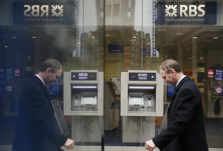 A pedestrian is reflected in an advertising board as he walks past a branch of The Royal Bank of Scotland in central London February 25, 2015. REUTERS/Stefan Wermuth