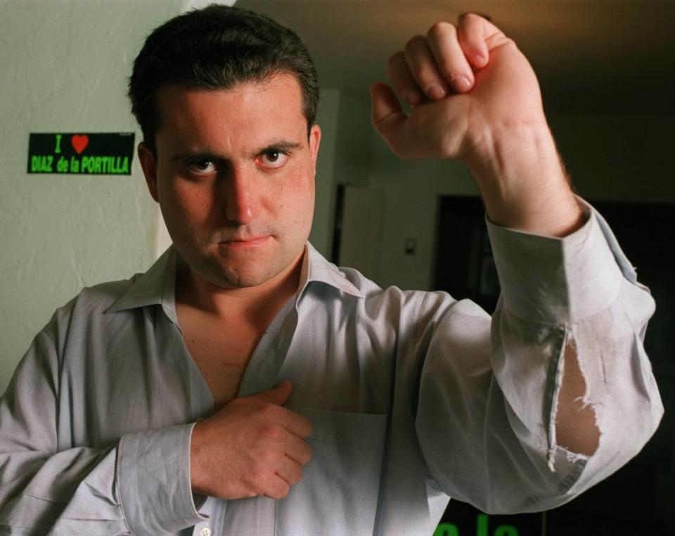 Renier Diaz de la Portilla, state legislator, shows off his ripped shirt and bruises he suffered during a fight at Radio Mambi in September 2000.