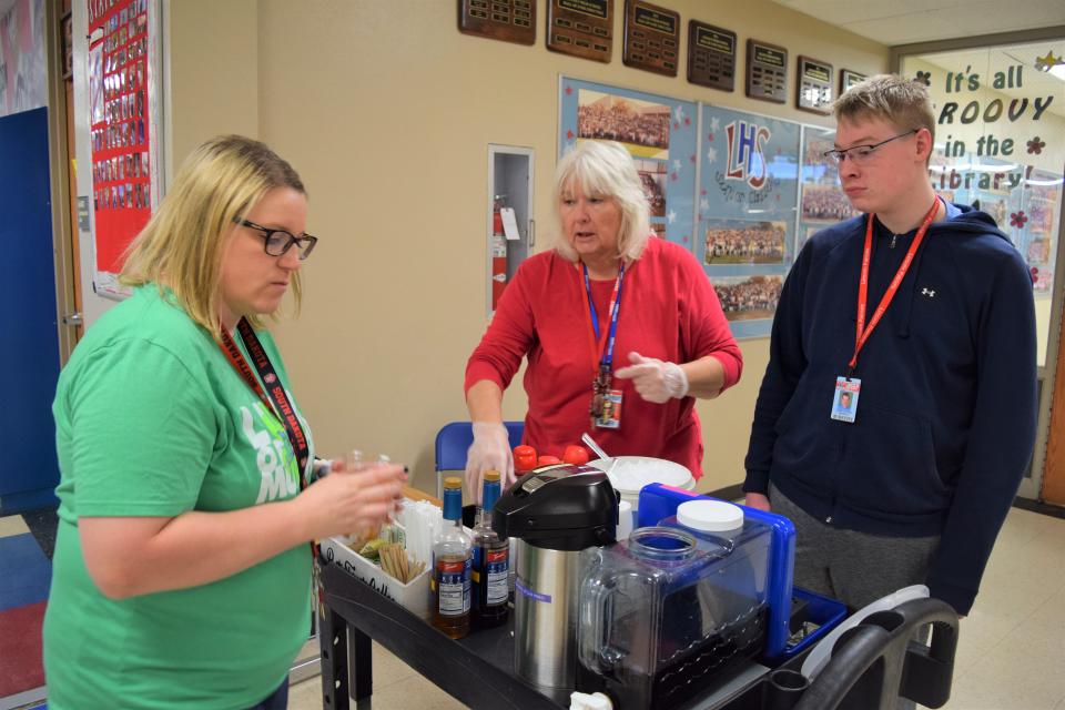 Lincoln High School journalism teacher Katie Kroeze (left) buys an iced coffee at the RISE coffee stand at LHS from Cassia Oaks (center), an education assistant, and Kaden Kittamus (right), a freshman at LHS, on May 20, 2022.