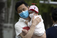 A man holds a child wearing masks to curb the spread of the coronavirus in Beijing on Wednesday, June 17, 2020. The Chinese capital on Wednesday canceled more than 60% of commercial flights and raised the alert level amid a new coronavirus outbreak, state-run media reported. (AP Photo/Ng Han Guan)