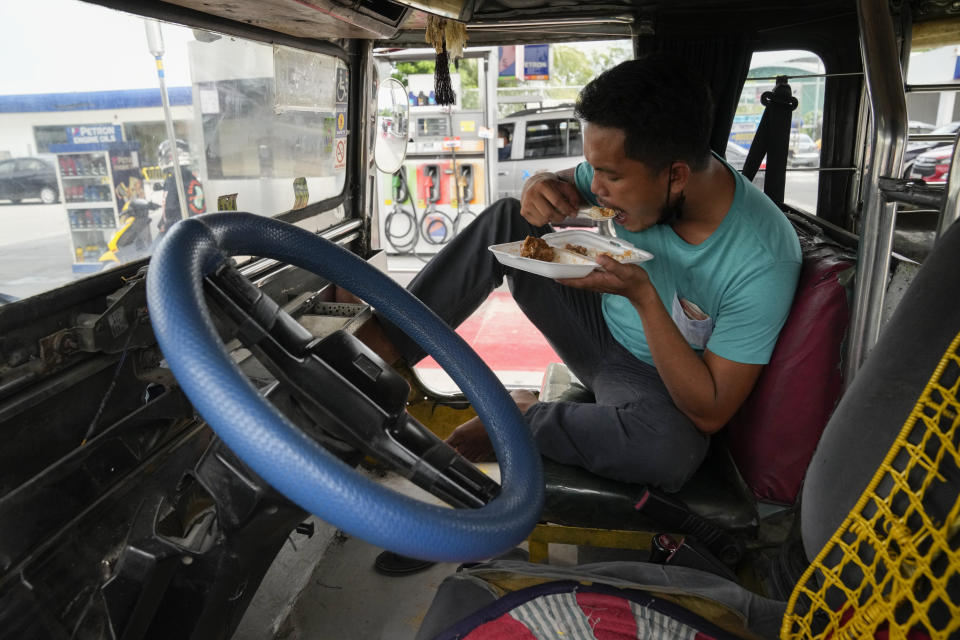 Passenger jeepney driver, Jet Marty dela Cruz, eats lunch inside his vehicle to save fuel instead of heading home as he takes a break at a gasoline station in Quezon City, Philippines on Monday, June 20, 2022. Around the world, drivers are looking at numbers on the gas pump and rethinking their habits and finances. (AP Photo/Aaron Favila)