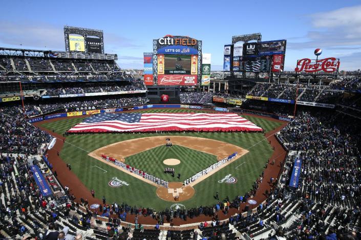 A giant American flag is unfurled before a baseball game between the New York Mets and Washington Nationals on opening day at Citi Field, Monday, March 31, 2014, in New York. (AP Photo/John Minchillo)