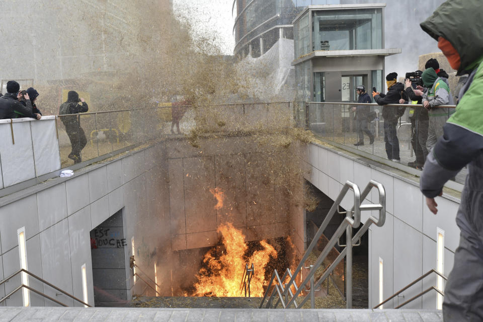 A protestor walks by a fire burning in a stairwell near the metro station during a demonstration outside the European Council building in Brussels, Tuesday, March 26, 2024. Dozens of tractors sealed off streets close to European Union headquarters where the 27 EU farm ministers are meeting to discuss the crisis in the sector which has led to months of demonstrations across the bloc. (AP Photo/Harry Nakos)