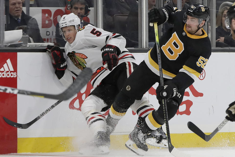 Chicago Blackhawks defenseman Connor Murphy (5) and Boston Bruins center Sean Kuraly (52) fight for position along the boards in the second period of an NHL hockey game, Thursday, Dec. 5, 2019, in Boston. (AP Photo/Elise Amendola)