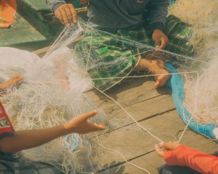 Fishermen untangling their fishing nets on the boat after a long day of fishing (1854 x WaterAid: Once Beating Heart/Calvin Chow 2022)