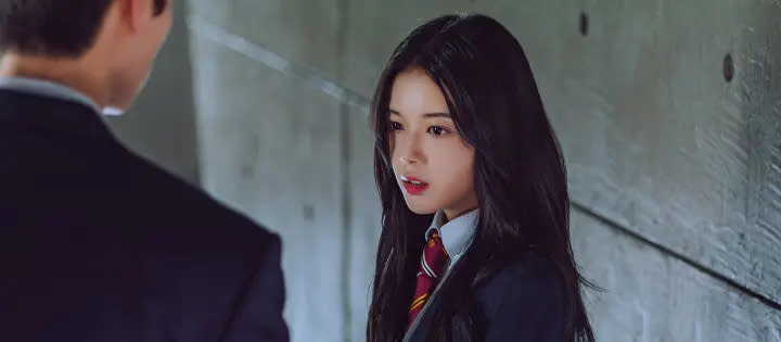 a girl in a school uniform stands with a boy who has his back to the camera