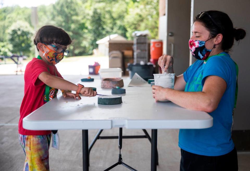 Erin Hoerner, right, who teaches special education at Glenn Elementary School during the school year, helps Jackson Wilfong, 6, make a plaster mold at The Hub Farm, an outdoor learning center in Durham, N.C., on Monday, June 21, 2021. At The Hub Farm, next door to Eno Valley Elementary School, students who did not struggle academically during the school year participate in outdoor learning activities.