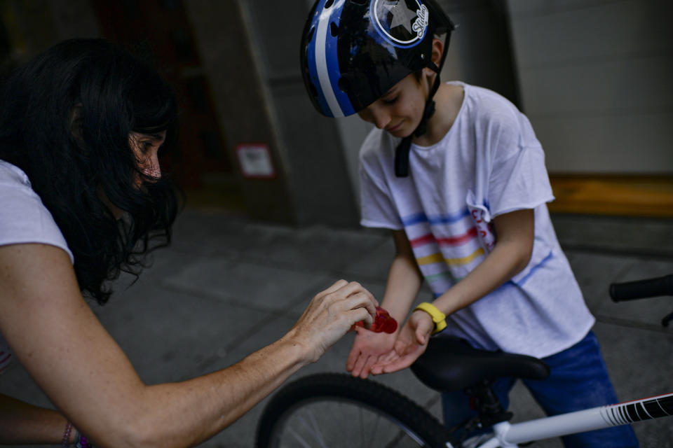 EDS NOTE : SPANISH LAW REQUIRES THAT THE FACES OF MINORS ARE MASKED IN PUBLICATIONS WITHIN SPAIN. A woman cleans the hands of a child to protect the coronavirus, in Pamplona, northern Spain, Sunday, April 27, 2020. On Sunday, children under 14 years old will be allowed to take walks with a parent for up to one hour and within one kilometer from home, ending six weeks of compete seclusion. (AP Photo/Alvaro Barrientos)