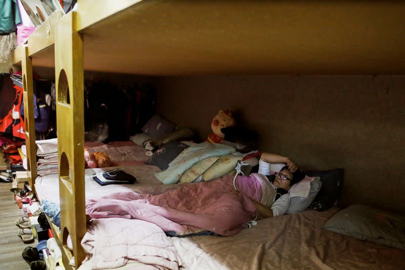 A masseur uses her phone while resting in her bed at the dorm area of a massage parlour in Taipei