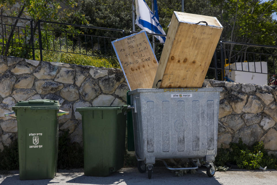 In this Friday, May 1, 2020 photo, the coffin that transported the body of a man who died from the coronavirus in the USA sits in a trash bin after his burial in east Jerusalem's Mount of Olives cemetery. Air travel to Israel has come to a near standstill due to coronavirus restrictions, but one type of voyage still endures: the final journey of Jews wishing to be buried in Israel. Families, the aviation industry and health workers are finding ways to keep the deceased flying in despite the challenges presented by the virus. (AP Photo/Ariel Schalit)
