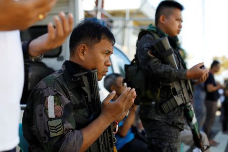 Philippines police officers perform Eid al-Fitr prayers outside a mosque inside city hall compound as government forces continue their assault against insurgents from the Maute group, who have taken over large parts of Marawi City, Philippines June 25, 2017. REUTERS/Jorge Silva