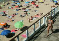 FILE - In this Wednesday, Aug. 5, 2020 file photo woman walks, wearing a face mask to protect against coronavirus, near the beach, in Saint Jean de Luz, southwestern France. Since Monday, 69 towns in western France imposed outdoor mask rules to slow the spread of coronavirus. Britain will require all people arriving from France to isolate for 14 days - an announcement that throws the plans of tens of thousands of holiday makers into chaos. The government said late Thursday Aug. 13, 2020 that France is being removed from the list of nations exempted from quarantine requirements because of a rising number of coronavirus infections. (AP Photo/Bob Edme, File)