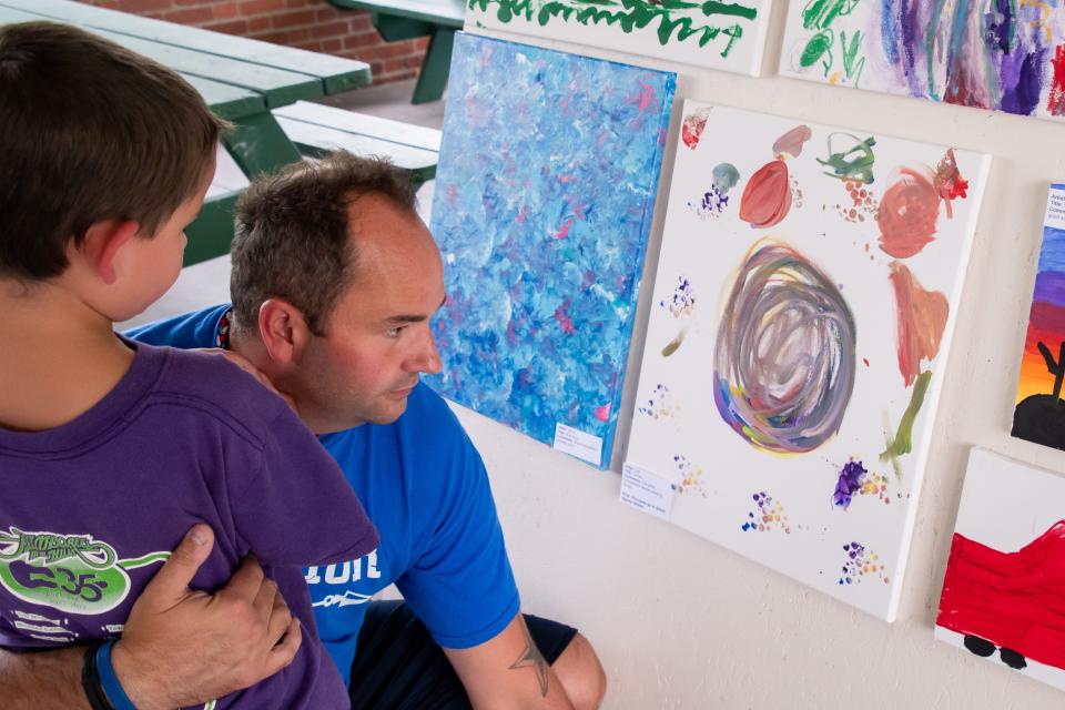 Justin Allen and his son Leo check out Leo's artwork entitled "Circles" at the Guernsey County Board of Developmental Disabilities art show at the Byesville Farmers Market.