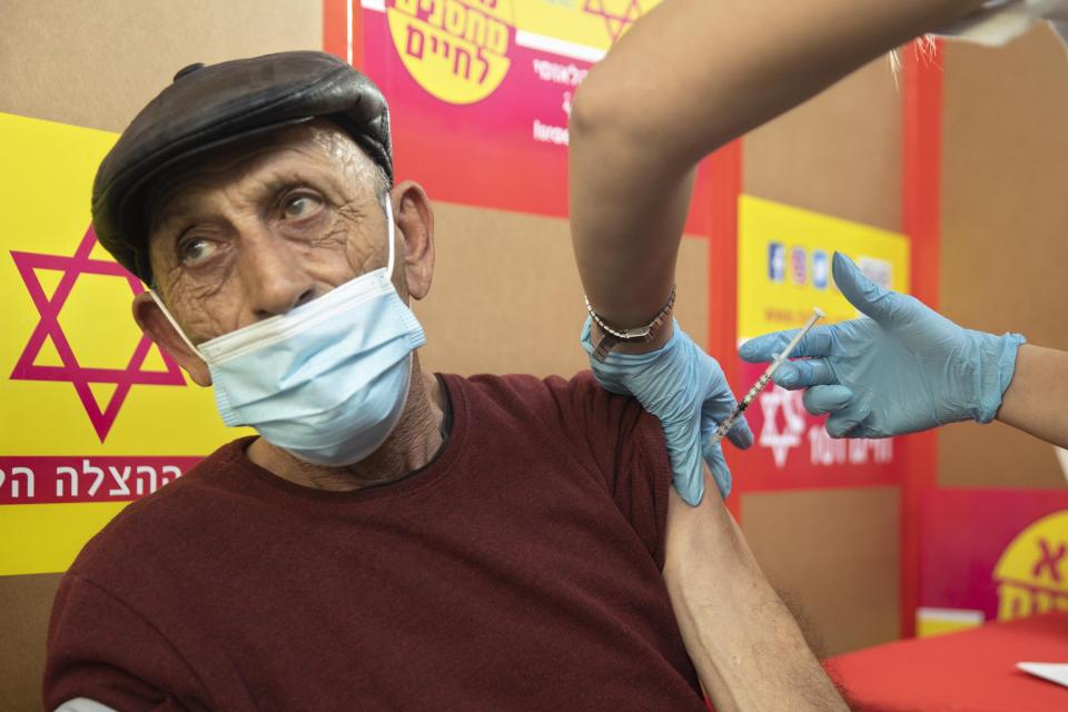 A Palestinian that works in Israel receives a Moderna COVID-19 vaccine at the Tarkumiya crossing between the West Bank and Israel, Monday, March 8, 2021. After delays, Israel started vaccinating Palestinians who work inside the country and its West Bank settlements on Monday, more than two months after launching an immunization blitz of its own population. (AP Photo/Sebastian Scheiner)