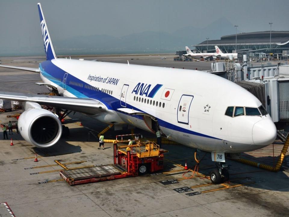 An All Nippon Airways plane being being loaded with baggage while parked at an airport.