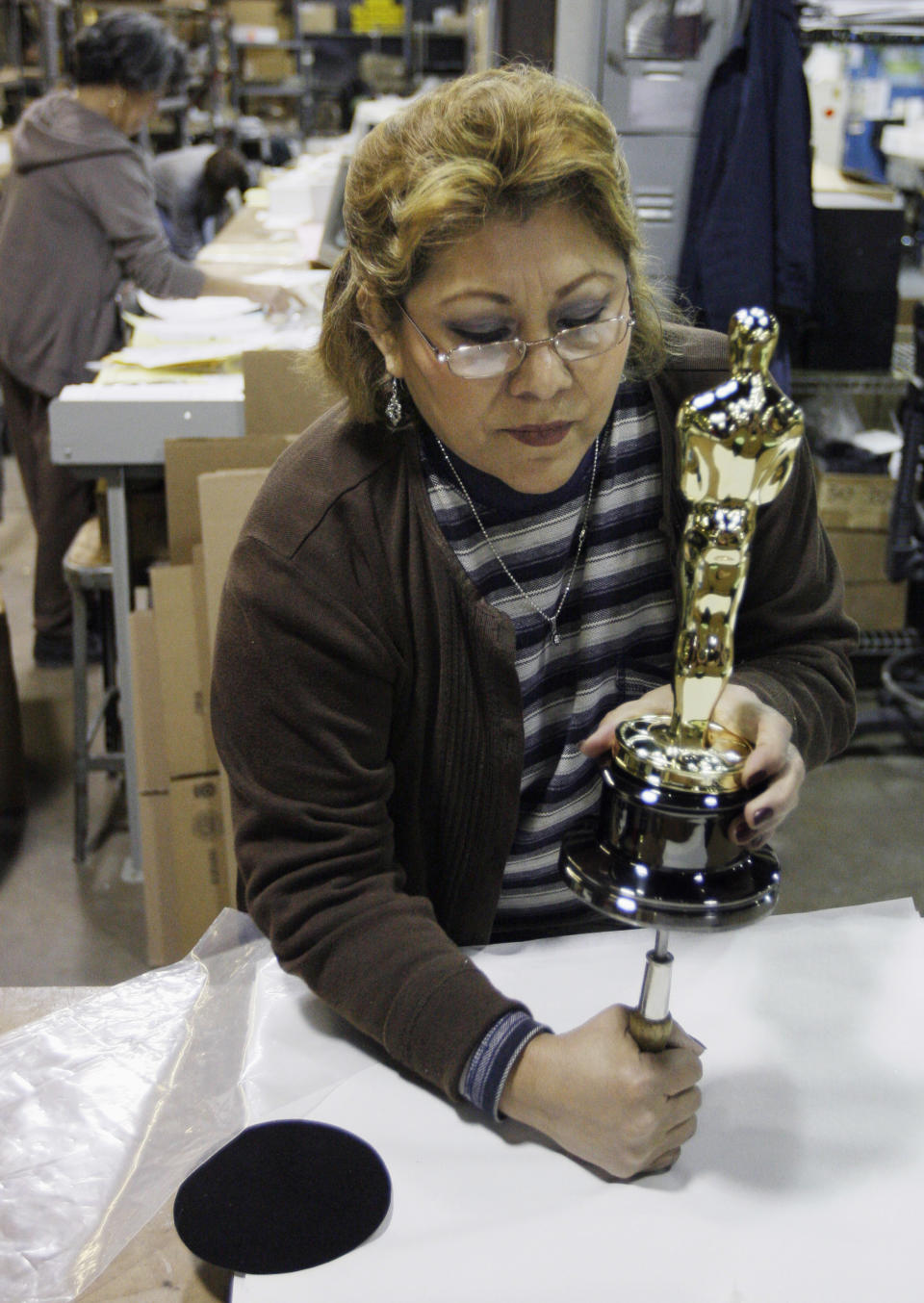FILE - In this Jan. 26, 2009 file photo, Bertha Fuentes assembles the statue and the base of an Oscar statuette at R.S. Owens & Co., in Chicago. The company said it will be laying off 95 workers on Dec. 17, 2012. The cuts come a month after R,.S. Owens announced it was being purchased on Dec. 17 by St. Regis Crystal Inc. of Indianapolis. The company has about 250 employees. A news release on the sale said the company will continue to make Oscar and Emmy statues in Chicago. They have been making the Oscar statues for about 30 years. (AP Photo/M. Spencer Green, File)