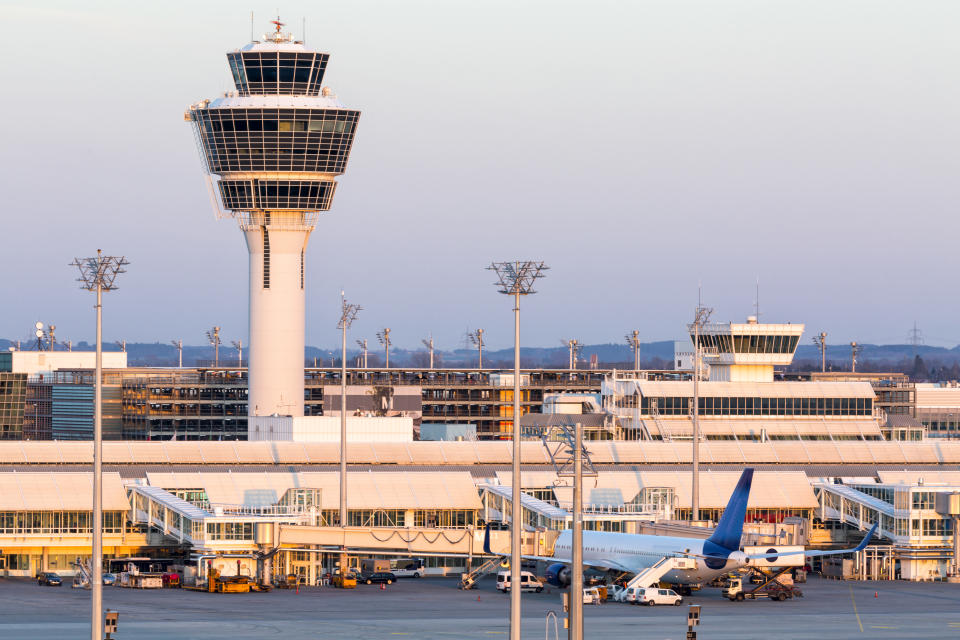 Franz-Josef-Strauss Munich airport with control tower, passenger airplane standing at the gates, apron area, long exposure with tripod.