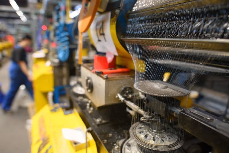 Threads run through a circular knitting head machine in the production hall of Mesh Pack. Plastic packaging is still ubiquitous in most supermarkets, and trying to reduce it should be a key priority, environmental activists say. A German firm has developed net packaging based on corn starch as a sustainable alternative. Klaus-Dietmar Gabbert/dpa