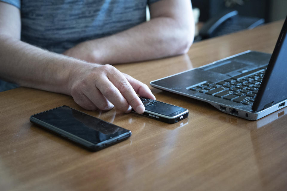 Oleksandr Vinkovskyi, director of a Kyiv manufacturing plant where visually impaired people worked, holds a phone set up to facilitate communication for the visually impaired during an interview in Kyiv, Ukraine, May 30, 2023, about the impacts of Russian attacks on his employees. "A visually impaired person goes to work not only to earn money, but also to communicate, interact, and be part of society in some way," said Vinkovskyi. "And I don't know how to estimate this loss." (AP Photo/Roman Hrytsyna)