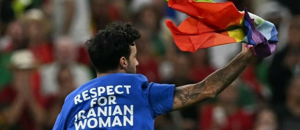 À la 51e minute de la rencontre de Coupe du monde entre le Portugal et l'Uruguay, ce lundi, un homme est entré sur la pelouse du stade de Lusail, au Qatar, muni d'un drapeau arc-en-ciel et vêtu d'un tee-shirt pour la défense des femmes iraniennes et de l'Ukraine.  - Credit:PABLO PORCIUNCULA / AFP