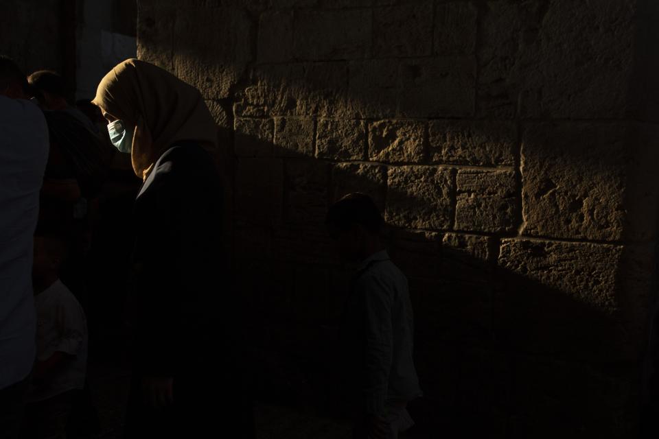 A woman wears a mask to help curb the spread of the coronavirus as she leaves prayers for Eid Al-Adha, or feast of sacrifice, in the Old City of Jerusalem, Friday, July 31, 2020. (AP Photo/Maya Alleruzzo)