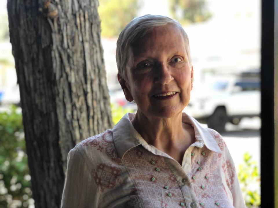 A woman seen from the shoulders up near a tree