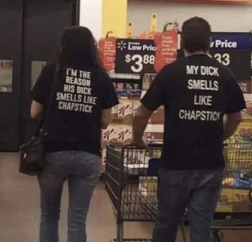 A couple wearing shirts where the woman's says, "i'm the reason his dick smells like chapstick"