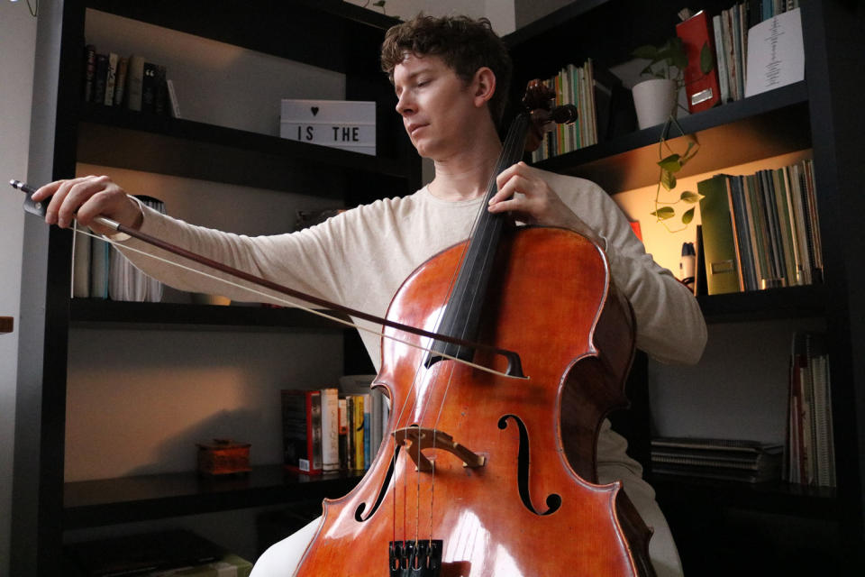 Joshua Roman practices the cello at his New York City home on Sunday. Long Covid left Roman with uncontrollable trembling, threatening his career. (Jonathan Yap)