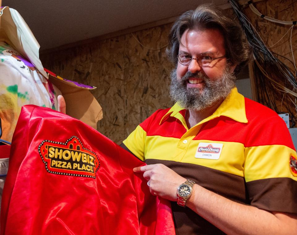 Damon Breland, owner of Smitty's Super Service, a collection of memorabilia from ShowBiz Pizza and Chuck E. Cheese in Sandy Hook, Miss., poses with an original ShowBiz Pizza Place jacket on Saturday, Jan. 8, 2022. Breland's collection includes original, fully-functioning animatronic robots and decor to recreate the restaurant's experience. 